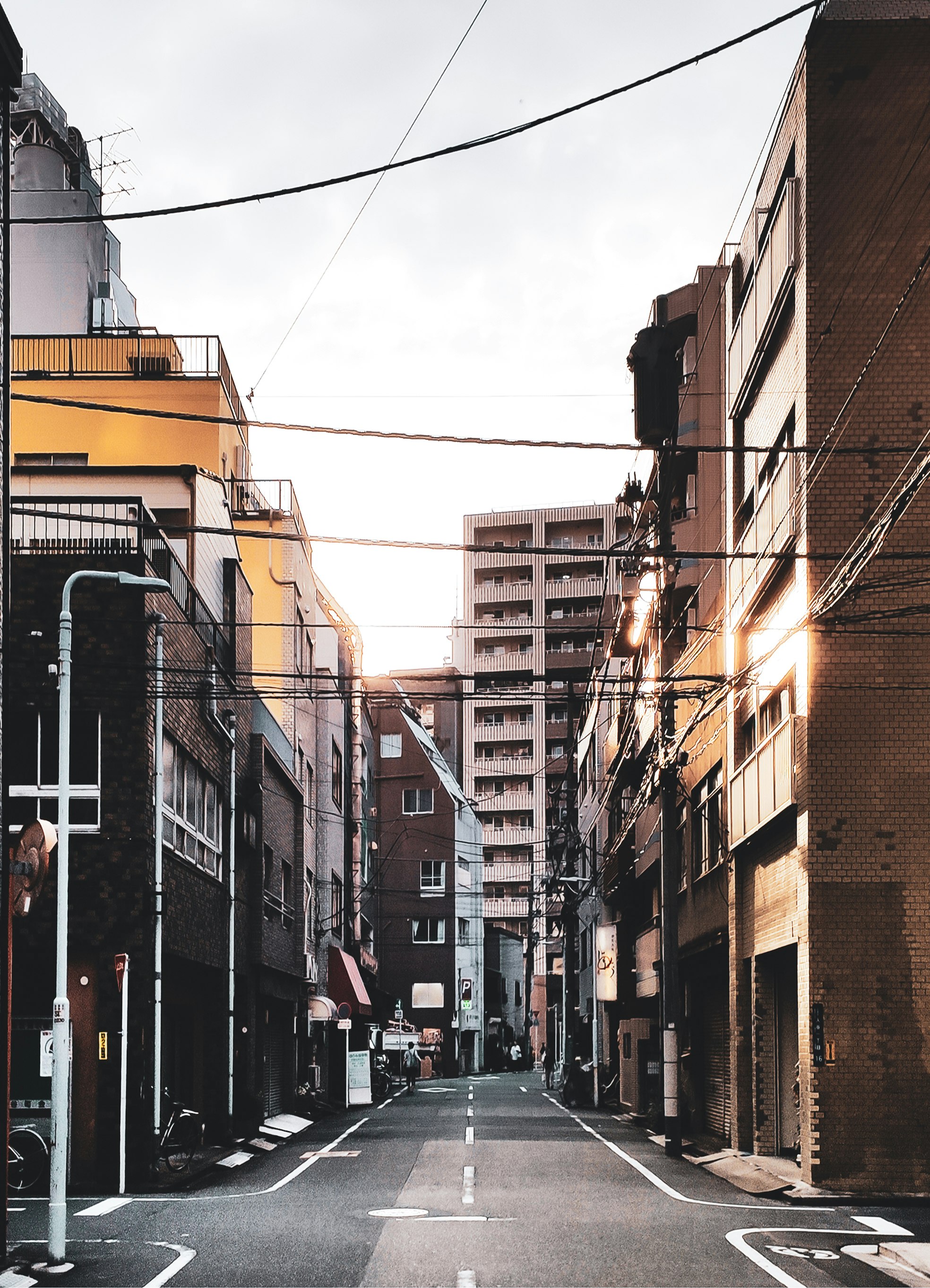 cars parked on side of the road in between buildings during daytime